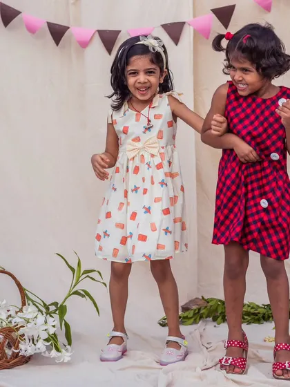 There's nothing more special than sisterly love. I designed these coordinating outfits to let their individual styles shine while still sharing a charming connection, one in a fun print and the other in a classic check.