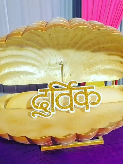 A unique prop for a naming ceremony, revealing the baby's name 'Dhruvik' in a golden clamshell.
