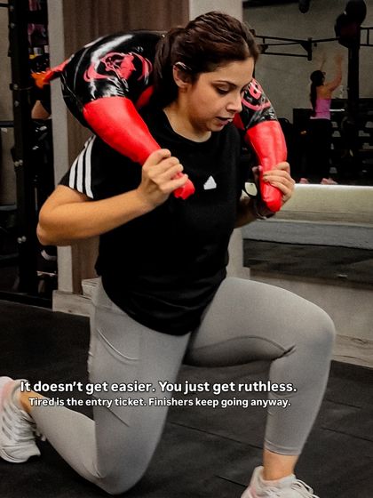 It doesn't get easier, you just get stronger. A client demonstrates incredible grit performing weighted lunges with a sandbag, a key exercise for building leg strength for Hyrox.