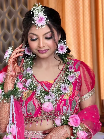 A close-up of the bride's Haldi makeup. The soft pink eyeshadow and matching lip color perfectly complement the floral jewelry and her vibrant outfit.