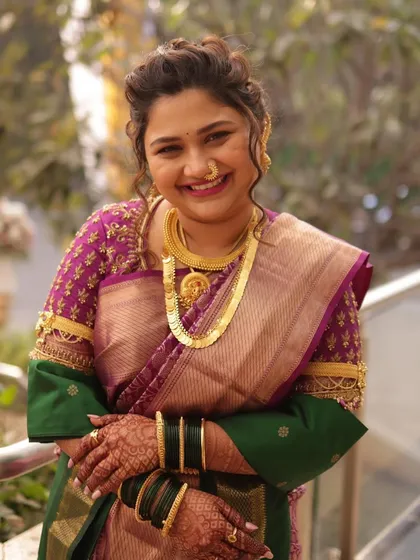 A close-up portrait of the bride, her happy smile capturing the joy of the day. The traditional gold necklace and nath complete her classic Maharashtrian bridal look.