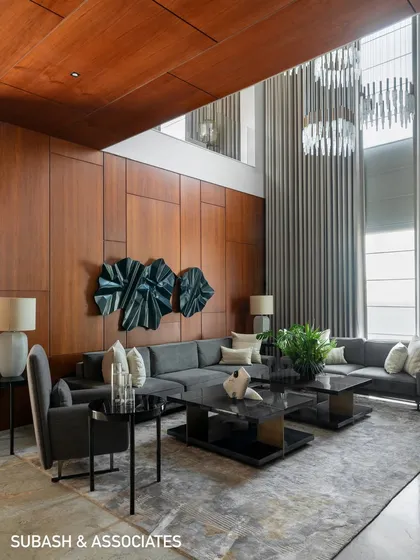 The double-height living room in this contemporary home uses expansive glass and soaring curtains to create a sense of grandeur. I balanced the scale with warm wood paneling and a monochromatic palette to keep the space inviting and elegant.