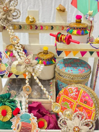 A multi-tiered Lohri hamper filled with a variety of decorated jars, boxes, and 'potlis'. The vibrant colors and traditional motifs make it a stunning centerpiece.