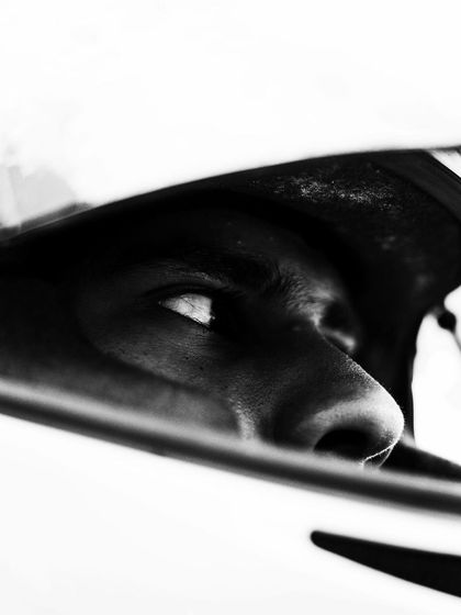 An artistic, high contrast shot of a driver's eyes reflected in his visor, showing the intense focus required in motorsport.