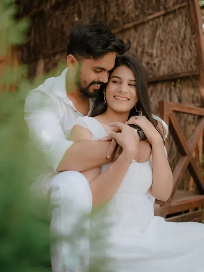 A joyful, candid moment on the steps of a rustic cabin. The couple's coordinated white outfits and genuine laughter make this a heartwarming and authentic pre-wedding photograph.