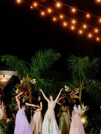 The dance floor comes alive under a canopy of twinkling lights, surrounded by palm trees.