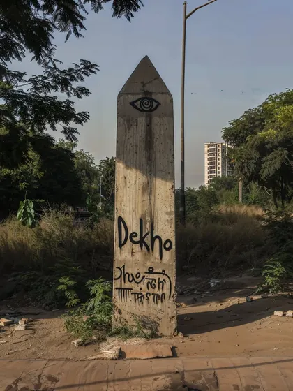 A mysterious concrete obelisk with an eye symbol and the word 'Dekho' graffitied on it. I create images like this to build a sense of mystery and a larger, unseen narrative in my world.