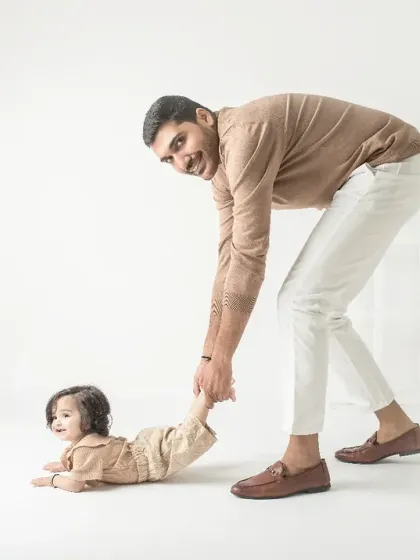 A playful tug on the leg. This fun, candid shot captures a silly moment between a father and his crawling baby.
