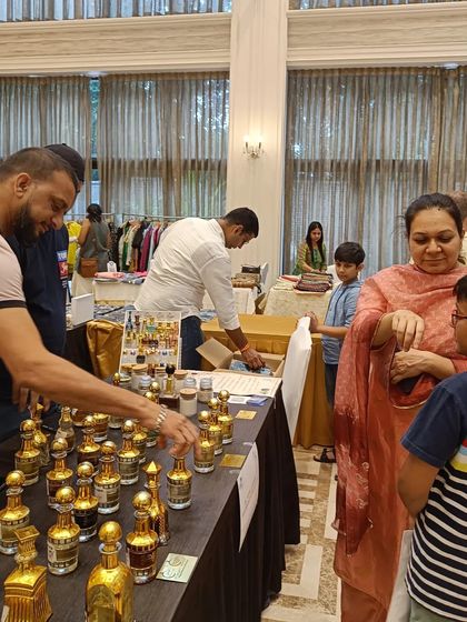 A family explores a stall of luxury fragrances, with the vendor guiding them through the different scents.