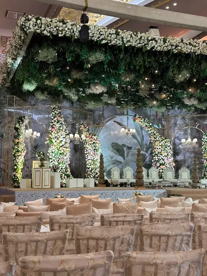A wide view of the vintage garden setup, with a lush green floral ceiling and elegant seating arrangements. The entire space is transformed into a timeless, romantic oasis.