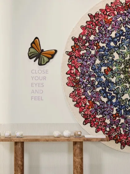 A close-up detail of the butterfly carpet installation at the Hands showroom. The accompanying text, 'Close your eyes and feel,' invites a sensory and emotional connection, moving beyond a purely visual experience.