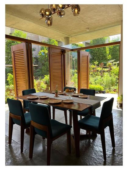 The dining room in 'Villa 34' is conceived as a pavilion within a garden, enclosed by glass and louvered wooden shutters. This design allows the space to be completely opened up, merging the act of dining with the experience of being in nature.