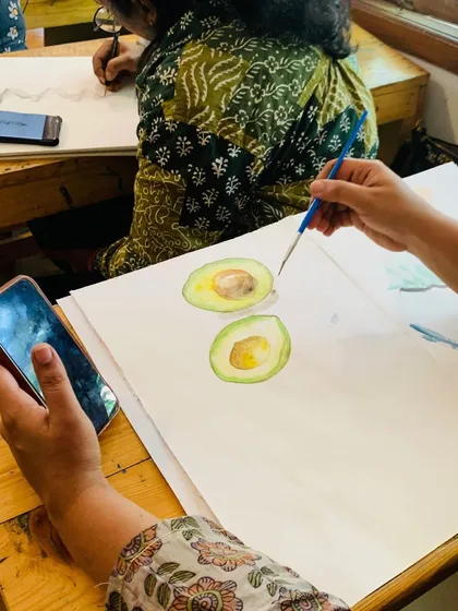 A student paints slices of avocado, carefully capturing the subtle variations in color and texture. This is a great example of the observational skills we teach.