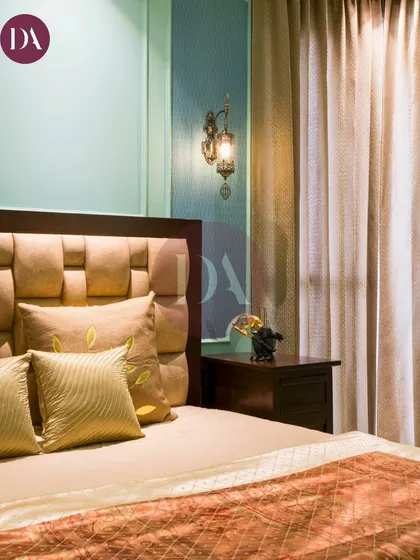 This bedroom design blends elegance and timeless charm. The soft, pastel green wall with classic molding provides a perfect backdrop for the luxurious, textured headboard.