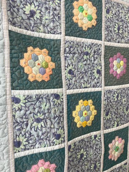 Detail of a hexagon quilt, showing the quilting around the floral appliqué.