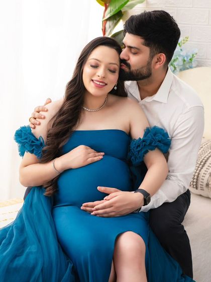 A tender moment of connection. The husband's gentle kiss on his wife's temple and their hands together on the bump create a portrait filled with love and serenity.
