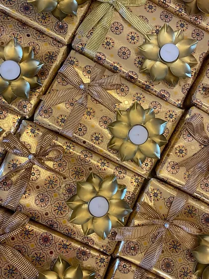 A stunning array of golden gift boxes created for a corporate client. Each box is topped with a beautiful lotus-shaped diya, making it a perfect festive gift.