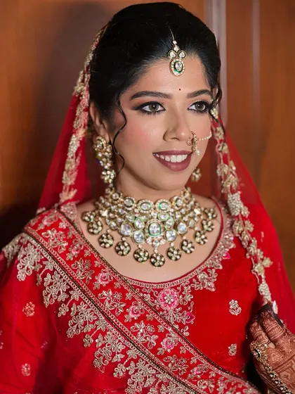 A classic red lehenga look for a beautiful bride. The makeup features a sharp winged liner and a bold lip.