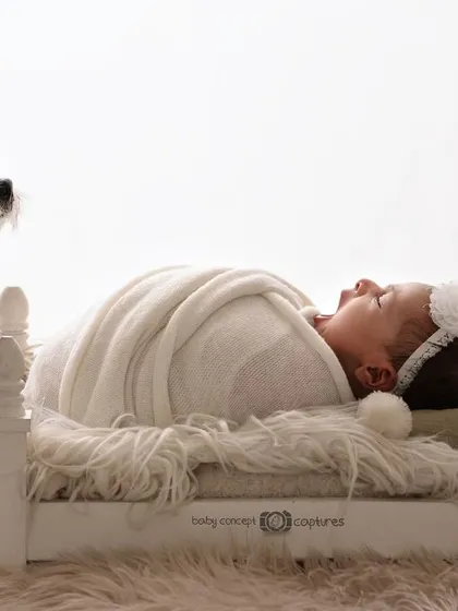 Yes, I absolutely photograph with pets. It can be chaotic, but capturing the bond between a newborn and a furry family member is always worth it. This high-key portrait of a baby and their watchful dog is a perfect example of the unique, heartwarming moments we can create.