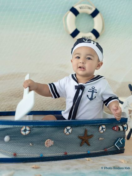 A close-up portrait of the baby boy in his sailor outfit, capturing his bright eyes and happy mood.