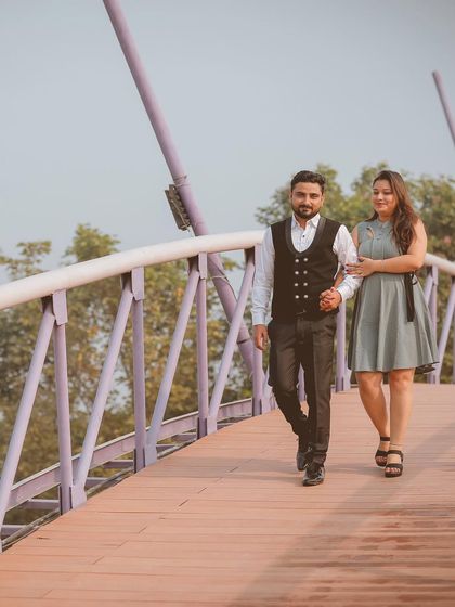 A classic walking shot of the couple on a bridge, capturing their elegant style and the beautiful surroundings.
