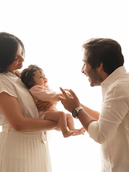A candid moment of play between parents and their baby girl. The bright, high-key lighting gives the photo a fresh and joyful feel.