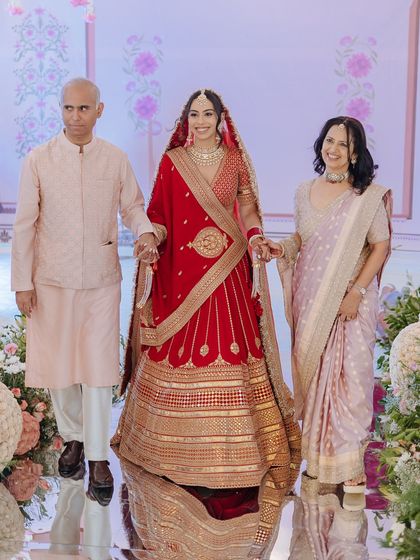 A bride walks down the aisle, escorted by her proud and smiling parents, a classic and emotional wedding moment.