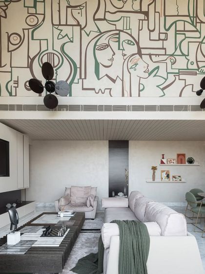 This high-wall mural tells the story of a family, weaving together personal symbols and abstract faces into a cohesive narrative. The earthy color palette creates a warm and inviting atmosphere in this living space.