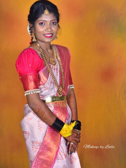 A smiling bride in her wedding attire. This studio shot showcases the harmony between her makeup, the puff-sleeved blouse, and the traditional jewelry.