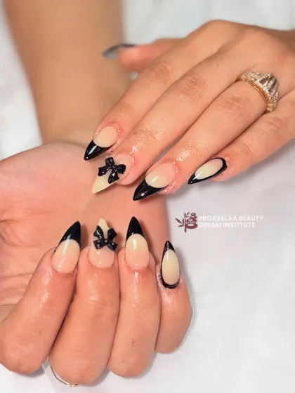 A close-up on the 3D bow accent nail, showing the detail and precision of the sculpting work against the clean, nude base.