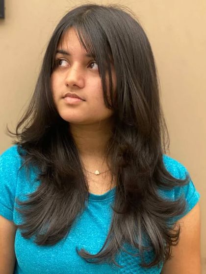 A client with a stunning new hairstyle, featuring soft layers and face-framing bangs for a confident and radiant look.