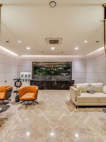 The reception area of the Embassy marketing office exudes luxury with its marble desk, designer furniture, and lush green wall feature. We specialize in creating premium commercial environments that impress potential clients.