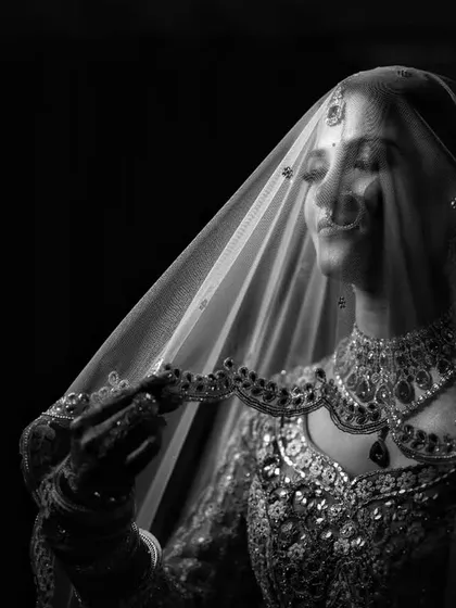 An elegant black and white portrait of a bride under her veil, her face softly lit.
