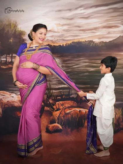 A beautiful family portrait with the older son holding his mother's saree pallu, set against a classic Ravi Varma-inspired backdrop.