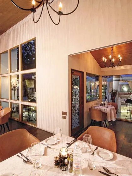 Our indoor dining room offers a warm and inviting atmosphere with its wooden floors and elegant chandeliers, perfect for any weather.