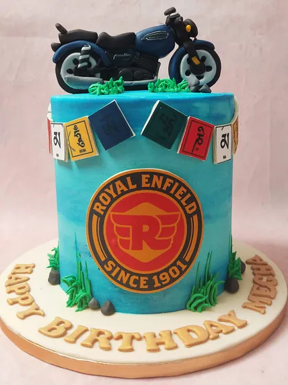 A frontal view of the motorcycle cake, showcasing the iconic Royal Enfield emblem against a vibrant blue backdrop.