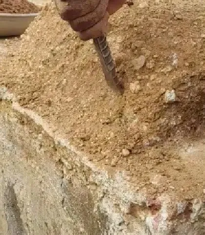 Testing the strength of a cob wall sample. We conduct these simple on-site tests to ensure the mud mix has the right composition and will result in a strong, durable structure.