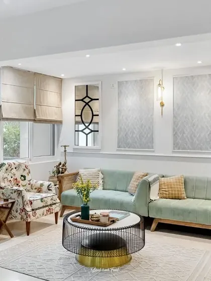 A bright and cheerful living room with a mix of floral and solid-colored seating. The wall features decorative mirrors and textured panels, adding depth and interest to the space.