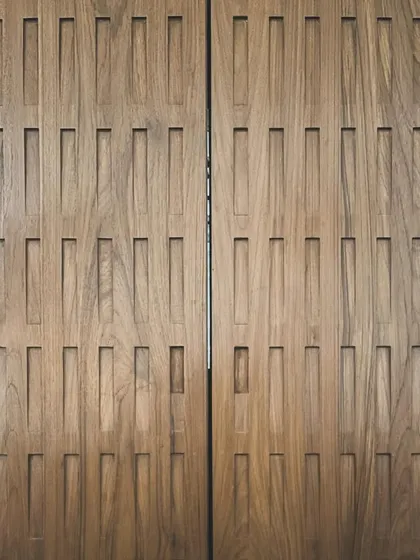 A close-up of custom wooden paneling designed for the Worli duplex. The rhythmic, carved pattern adds texture and a layer of detailed craftsmanship to the interior walls.