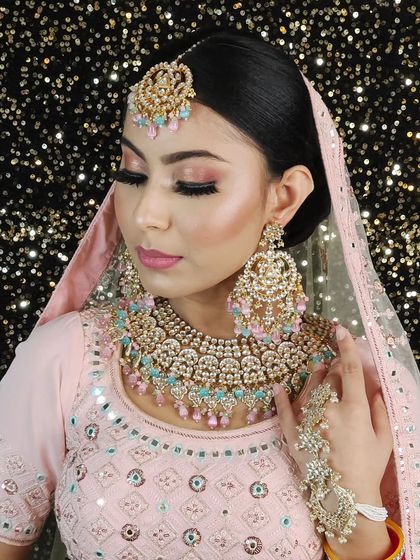 A soft and pretty bridal look with a heavy Kundan set featuring pastel pink and mint beads. The matching hathphool completes the coordinated ensemble.