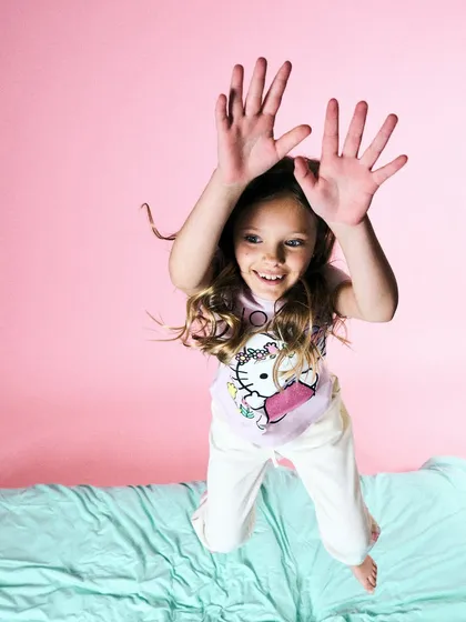 Pure, uninhibited joy. For this studio shot, we just let her jump on the bed. Sometimes the best commercial shots come from letting kids be kids. The lighting is bright and even to match the playful mood.