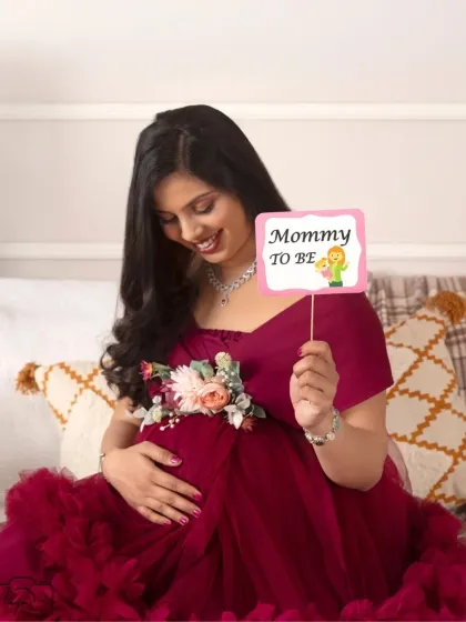 A sweet and joyful shot with a "Mommy to be" prop. Her smile is radiant and full of happiness.