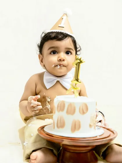 A sweet moment of contemplation before the cake destruction begins. Dressed in a party hat and bowtie, he looks at his birthday cake, ready for the fun to start.