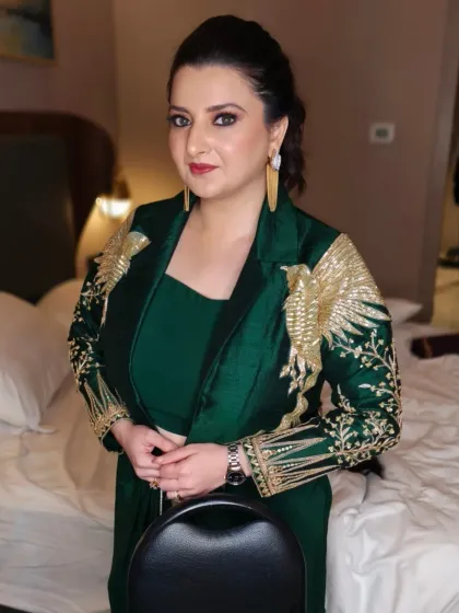 This is a powerful and sophisticated party look, perfect for a cocktail night or formal function. The makeup features a bold red lip and shimmering eyeshadow, paired with a sleek, pulled-back hairstyle that highlights the client's features and her stunning emerald green outfit.