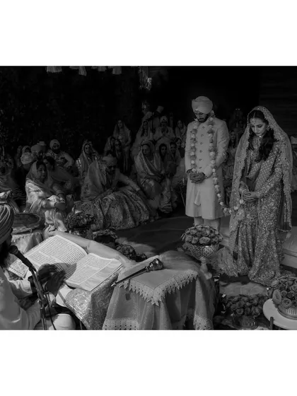 A moment of quiet prayer during Noor and Dhruv's Anand Karaj ceremony. This black and white photograph emphasizes the spiritual and traditional aspects of a home wedding, focusing on the reverence of the moment.