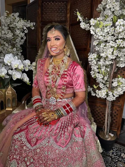 Our beautiful bride Anjali, looking radiant on her wedding day. Her bright pink lehenga is paired with dramatic eye makeup and a full set of traditional jewelry.