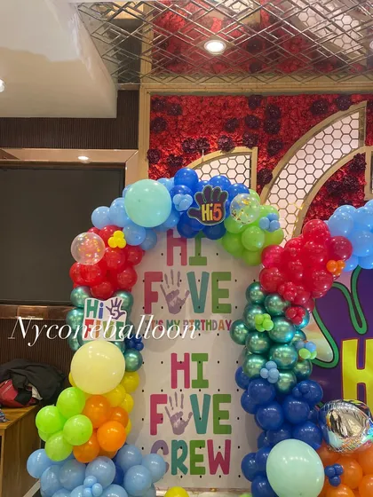 A closer look at the backdrop for the 'Hi-5' themed party. It features custom printed panels and is framed by a multi-colored balloon arch, creating a perfect photo spot.