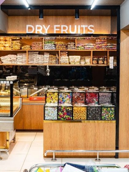 Specialty sections like the dry fruits and pickle counter are given a distinct identity with warm wood finishes and clear signage. This helps customers easily locate specific items and enhances the perception of quality.