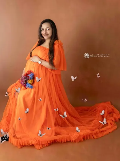 A touch of whimsy with fluttering butterflies around a brilliant orange gown. This creative shot adds a layer of magic and fantasy to the maternity session.