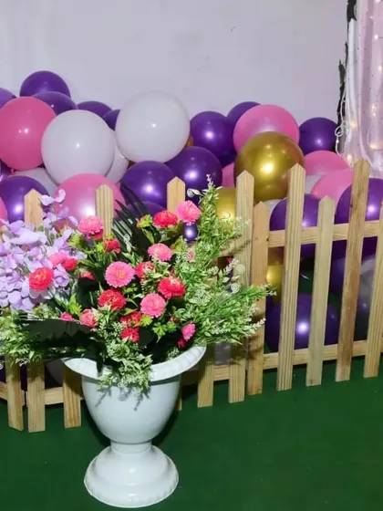 A detail shot from the pink and purple party, showing a floral arrangement in front of a charming picket fence, adding a touch of garden-party elegance.